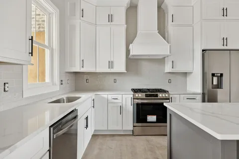 a kitchen with granite countertop white cabinets and stainless steel appliances