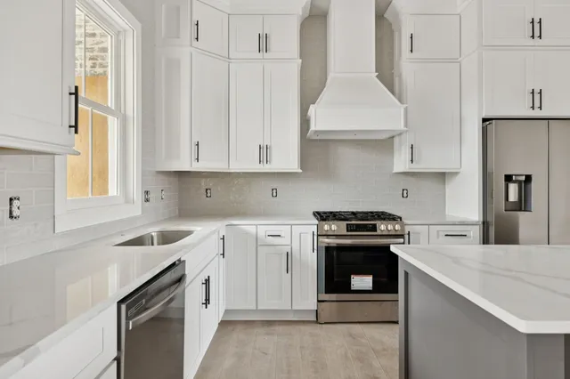 a kitchen with granite countertop white cabinets and stainless steel appliances