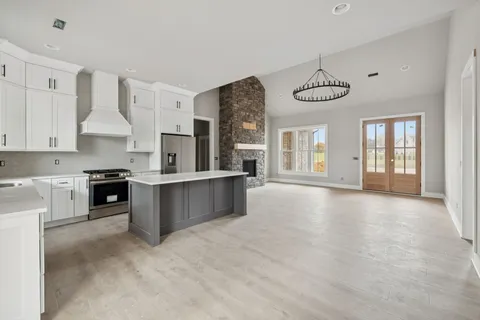 a large kitchen with stainless steel appliances granite countertop a stove a sink dishwasher a refrigerator white cabinets and wooden floor