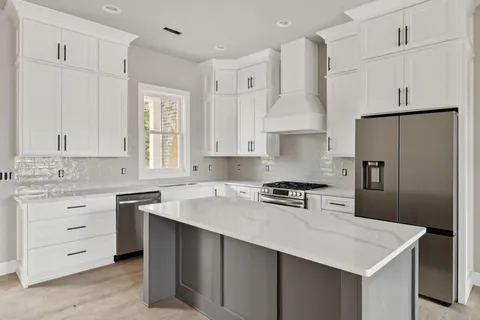 a kitchen with white cabinets sink and refrigerator