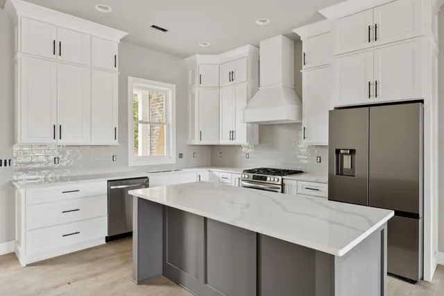 a kitchen with white cabinets sink and refrigerator