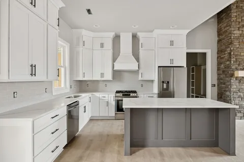 a kitchen with kitchen island granite countertop a sink cabinets and stainless steel appliances