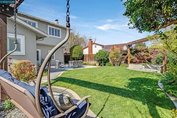 a view of a backyard with couches potted plants and large tree