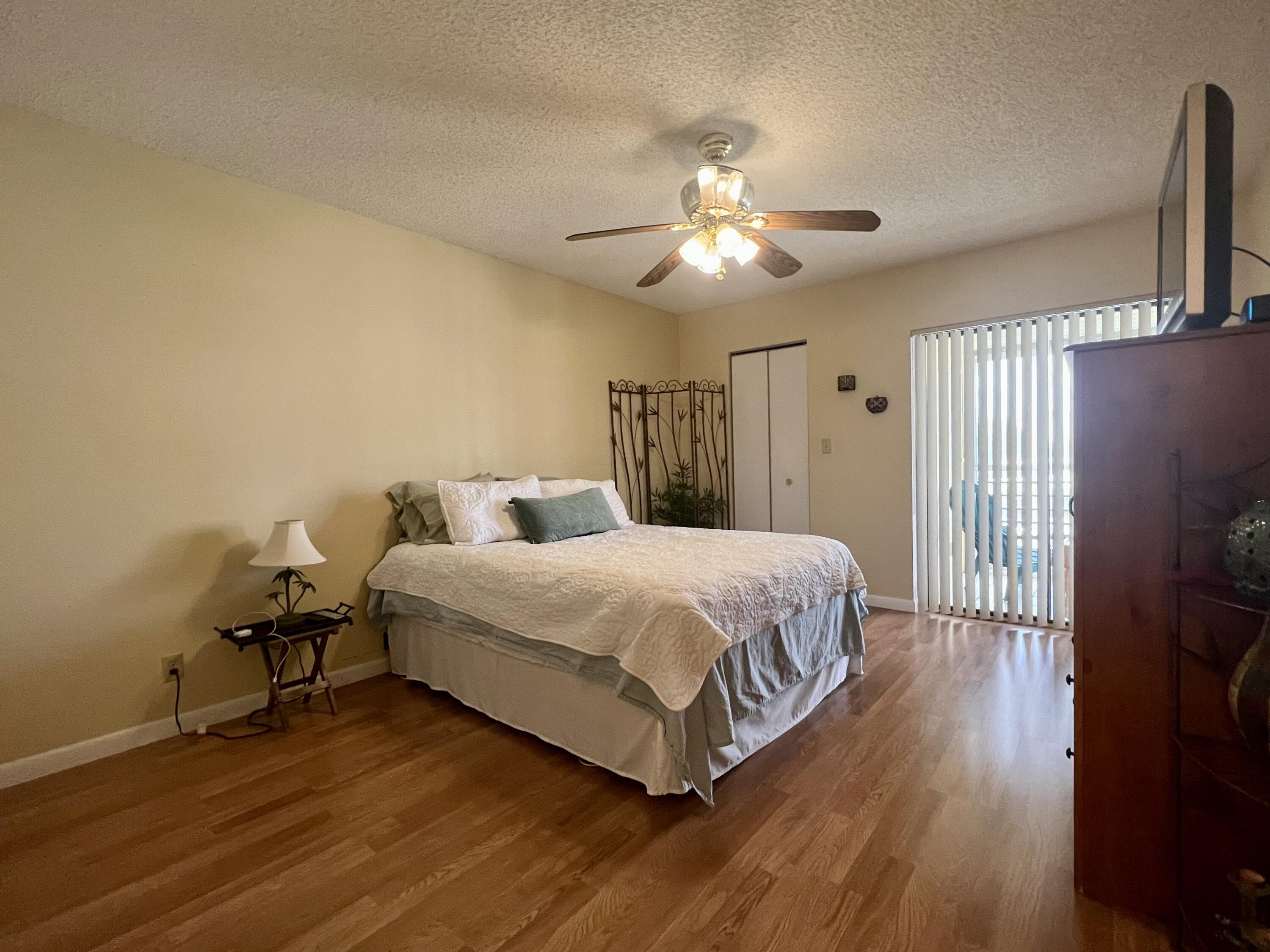 3154 Via Poinciana, Unit 214 Lake Worth, FL 33467 - Photo 13 of 23 a bedroom with a bed and a chandelier