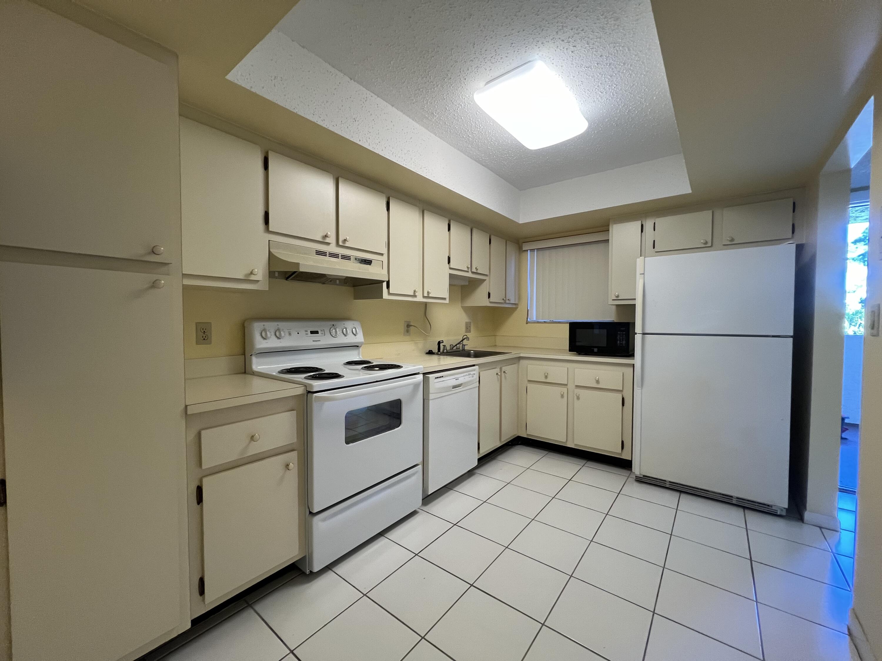 3154 Via Poinciana, Unit 214 Lake Worth, FL 33467 - Photo 4 of 23 a kitchen with a white cabinets and white appliances