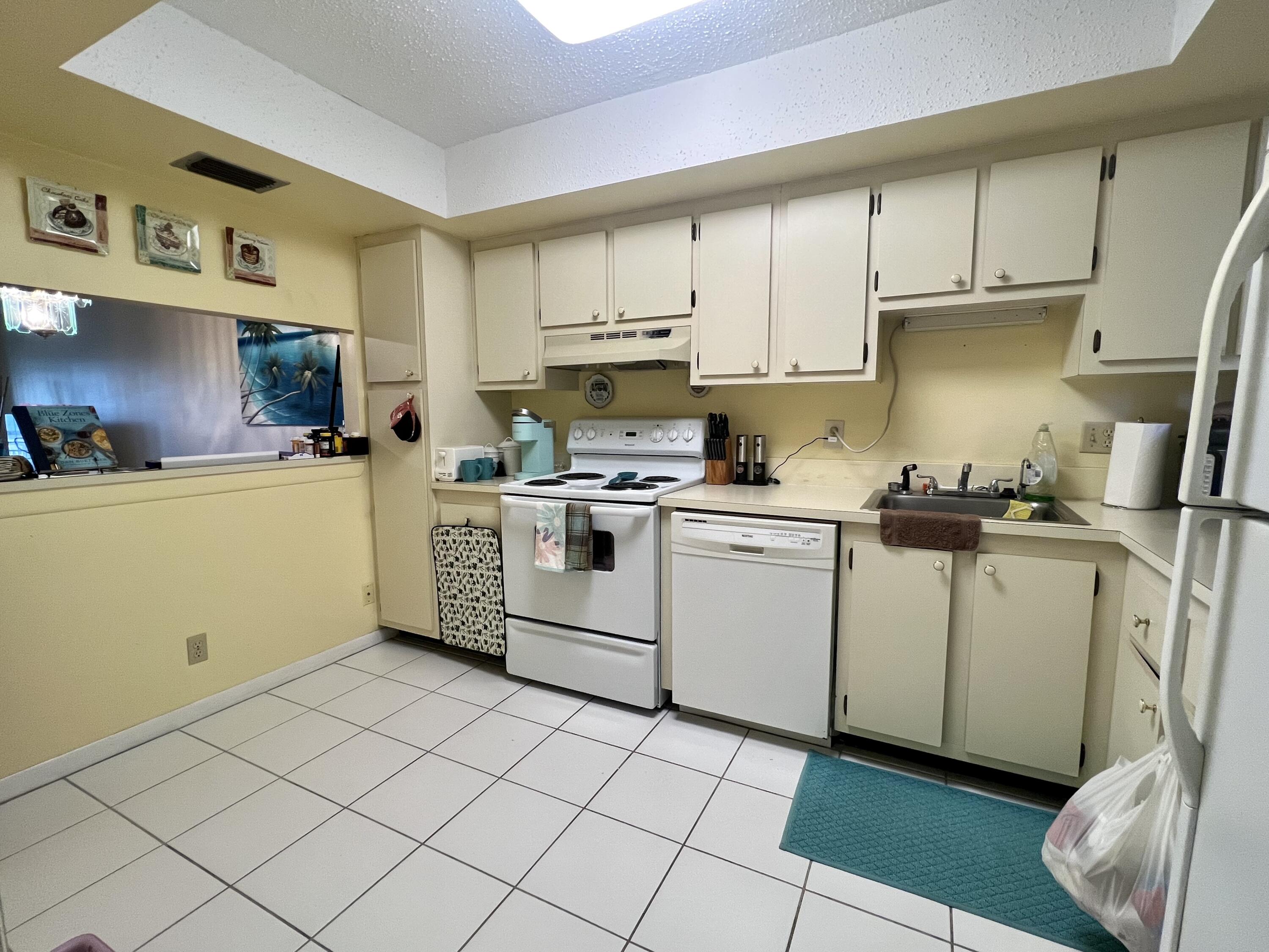 3154 Via Poinciana, Unit 214 Lake Worth, FL 33467 - Photo 5 of 23 a kitchen with cabinets a sink and white appliances