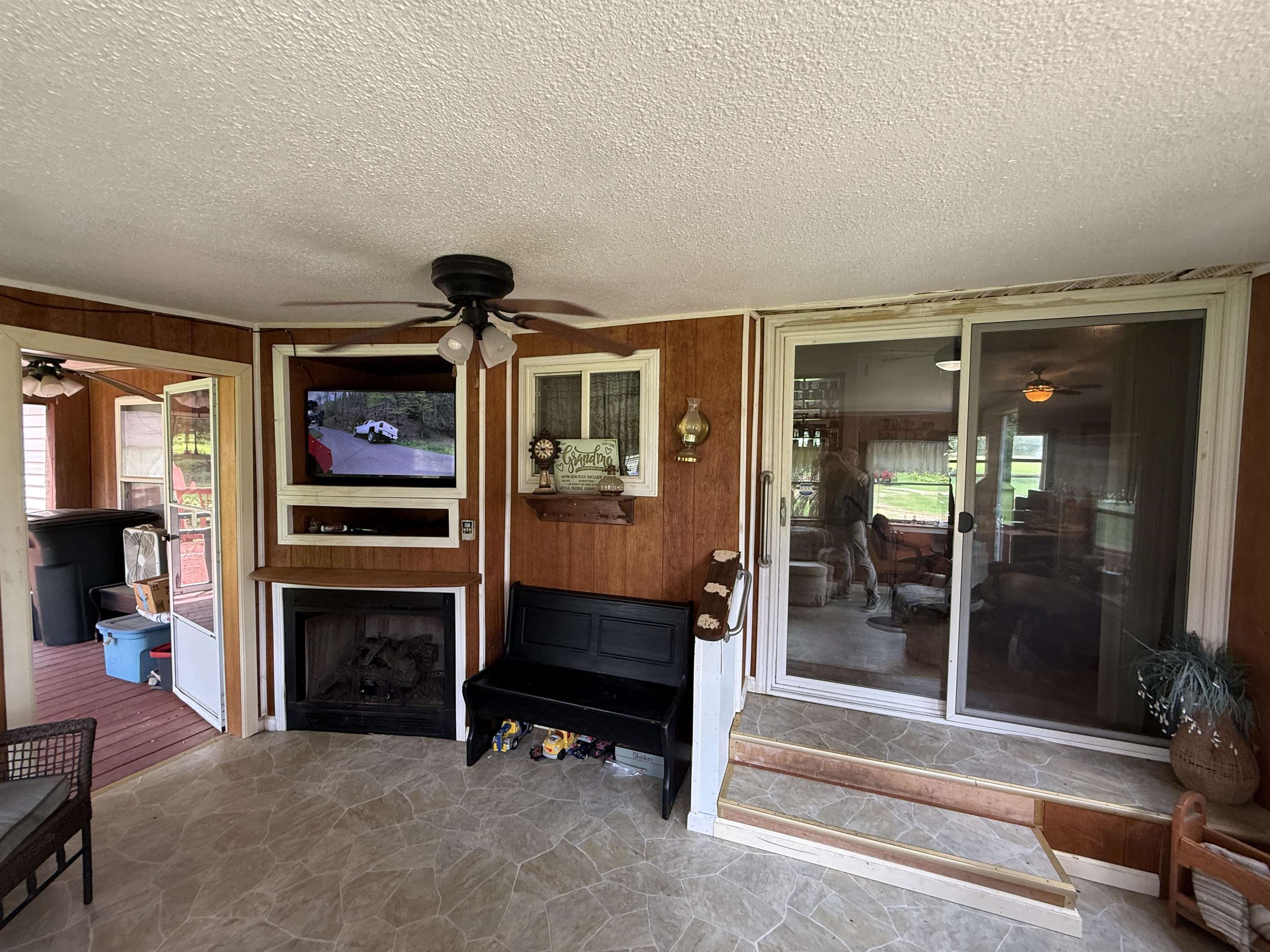 2201 Robert Johnson Road Covington, TN 38019 - Photo 16 of 25 Enclosed porch featuring flagstone-style flooring, wood-paneled walls, and a built-in media center with a fireplace