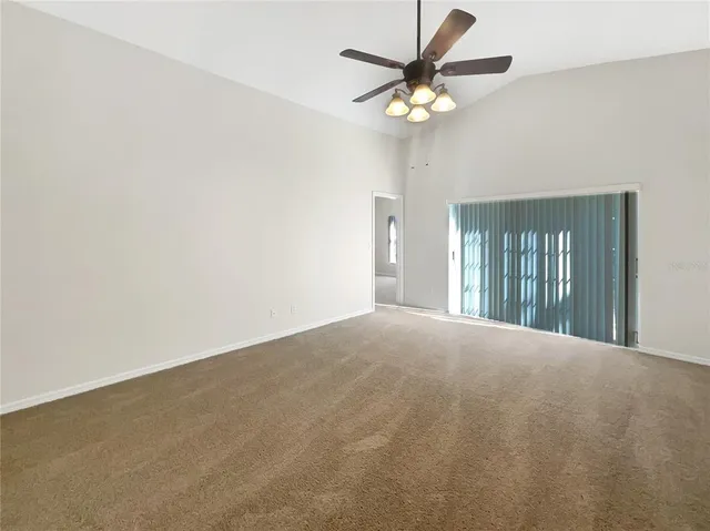 a view of an empty room with a chandelier fan