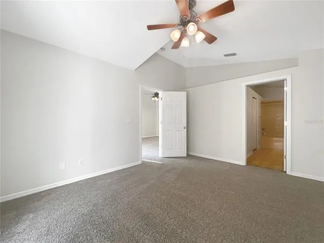 a view of an empty room and chandelier fan