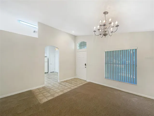a view of an empty room with chandelier and a window