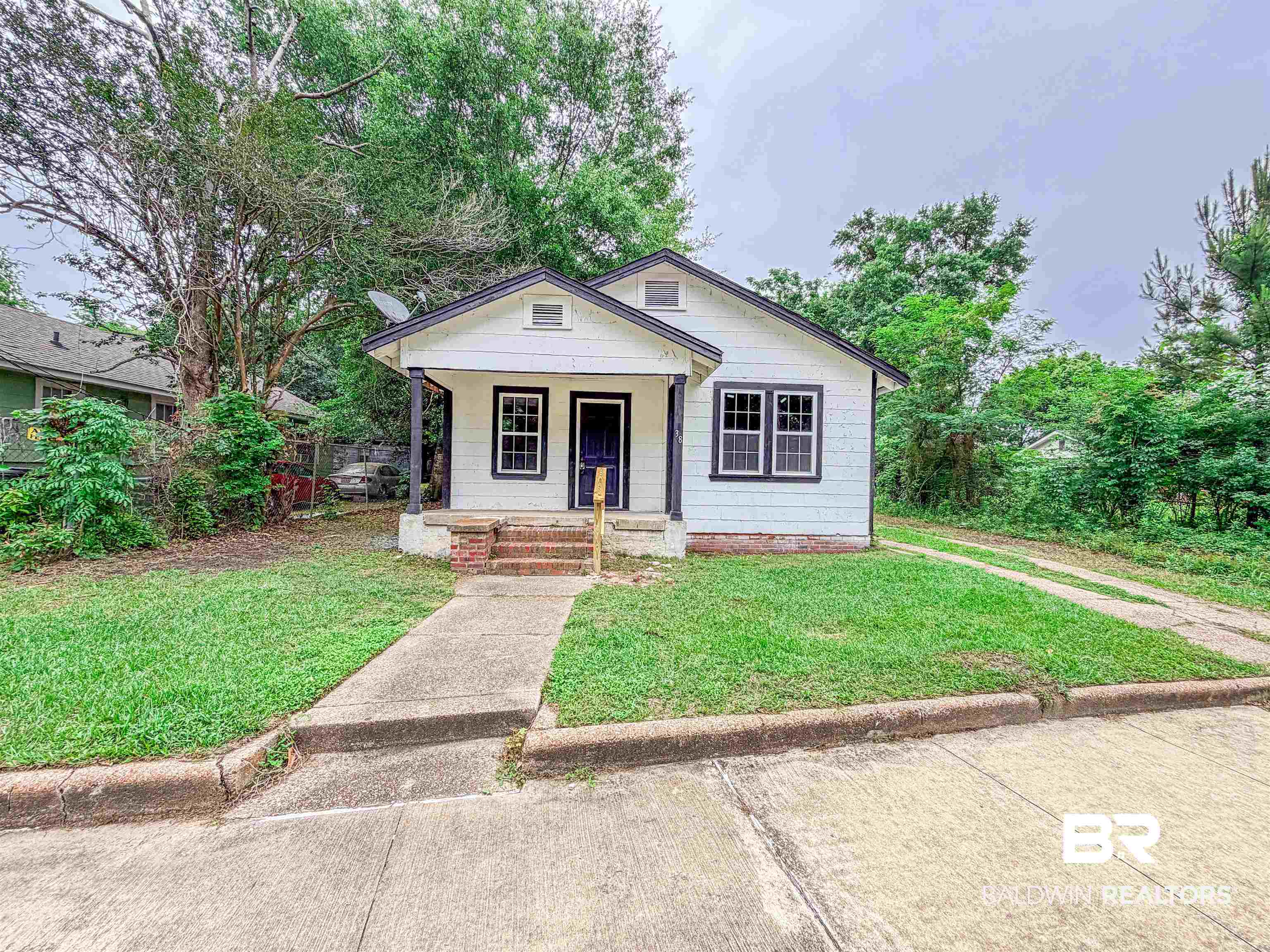 38 Flock Avenue Mobile, AL 36610 - Photo 26 of 27 Single-story residence featuring white siding, a dark trim, and a covered front porch with brick steps