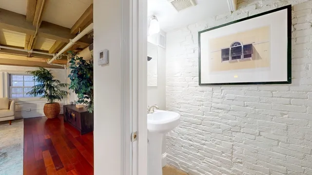 a view of a hallway with wooden floor and a bathroom view