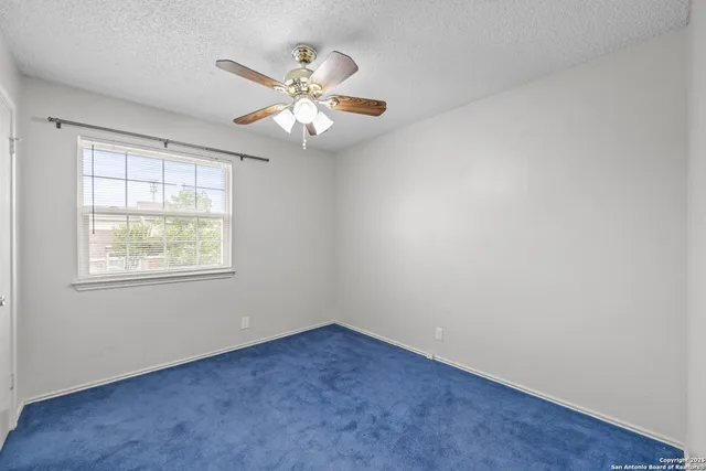 an empty room with windows and fan