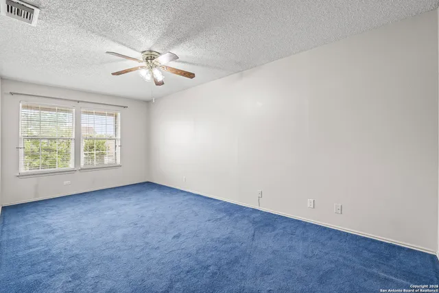 an empty room with windows and fan