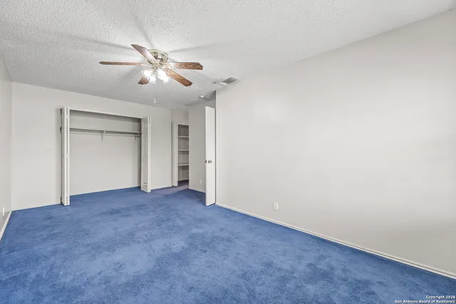 an empty room with closet and a chandelier fan