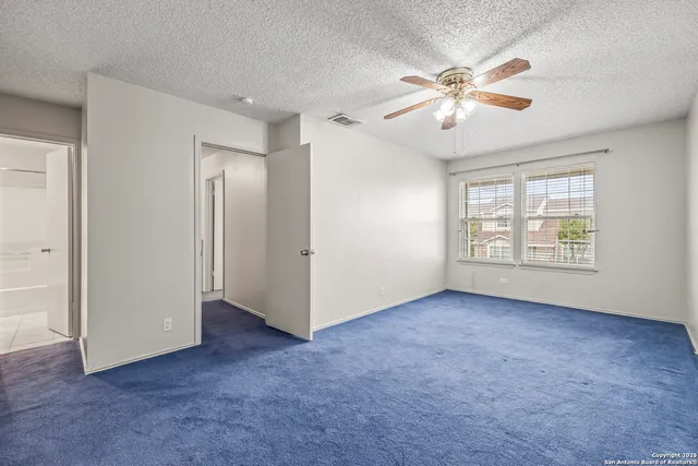 an empty room with fan and windows