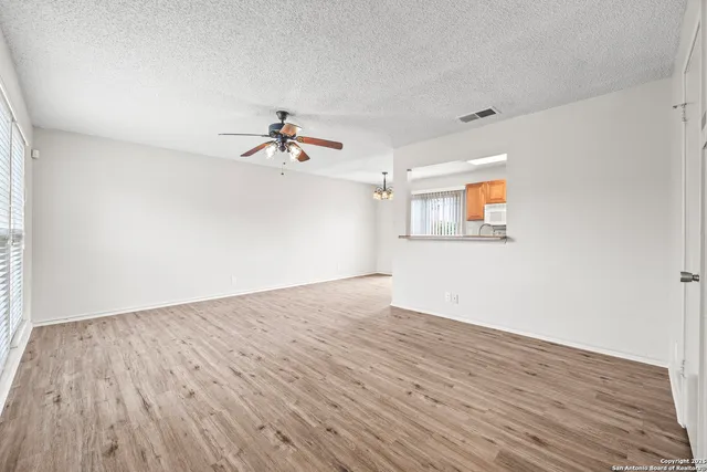 a view of a room with wooden floor and a ceiling fan