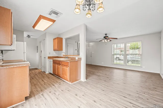 a kitchen with stainless steel appliances granite countertop a stove a sink dishwasher and a refrigerator with wooden floor