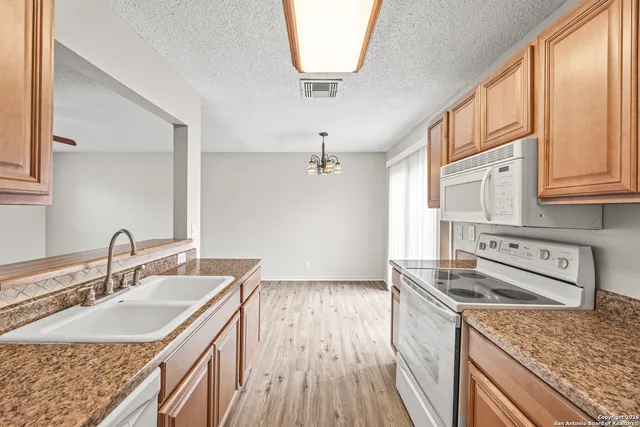 a kitchen with stainless steel appliances granite countertop a sink dishwasher stove and refrigerator with wooden floor