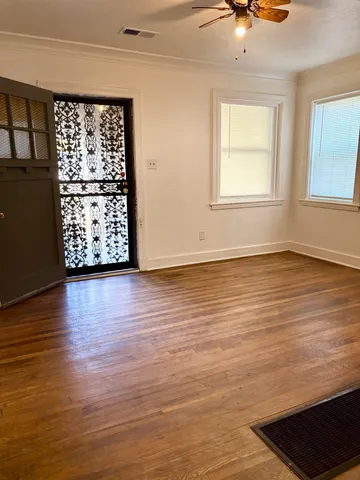 a view of an empty room with wooden floor and a window