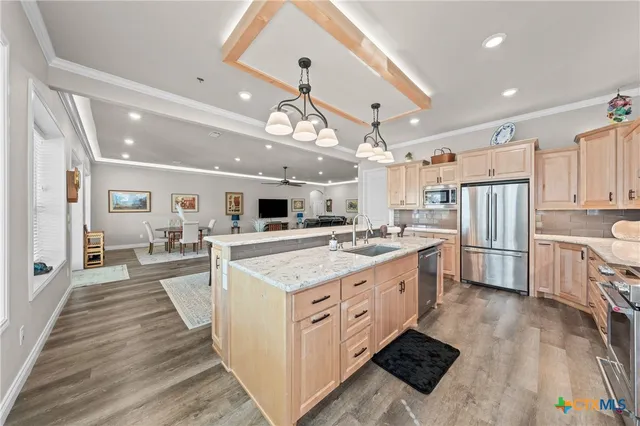 a large kitchen with stainless steel appliances kitchen island granite countertop a large counter top and wooden floors