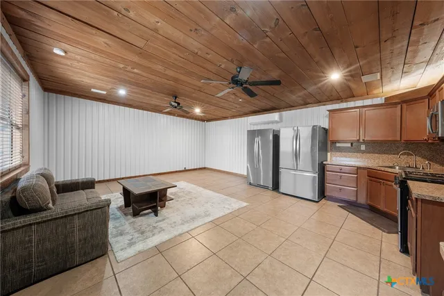a living room with stainless steel appliances kitchen island granite countertop a sink cabinets and stove top oven