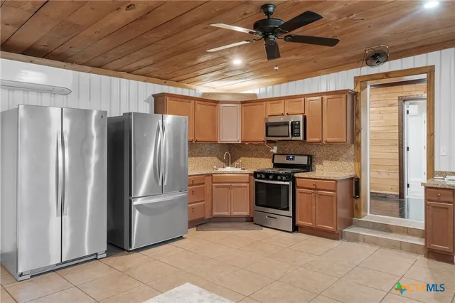 a kitchen with stainless steel appliances granite countertop a refrigerator and a stove top oven