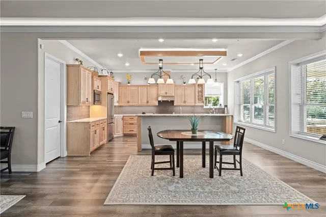 a kitchen with stainless steel appliances kitchen island granite countertop a table chairs sink and cabinets