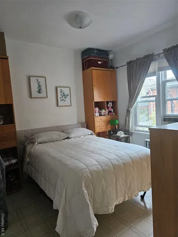 a bedroom with a bed large mirror and window