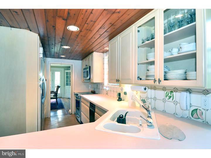344 Penn Road Wynnewood, PA 19096 - Photo 7 of 25 a kitchen with stainless steel appliances a sink a refrigerator a dining table and chairs with wooden floor