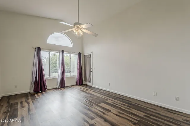 an empty room with wooden floor fan and windows
