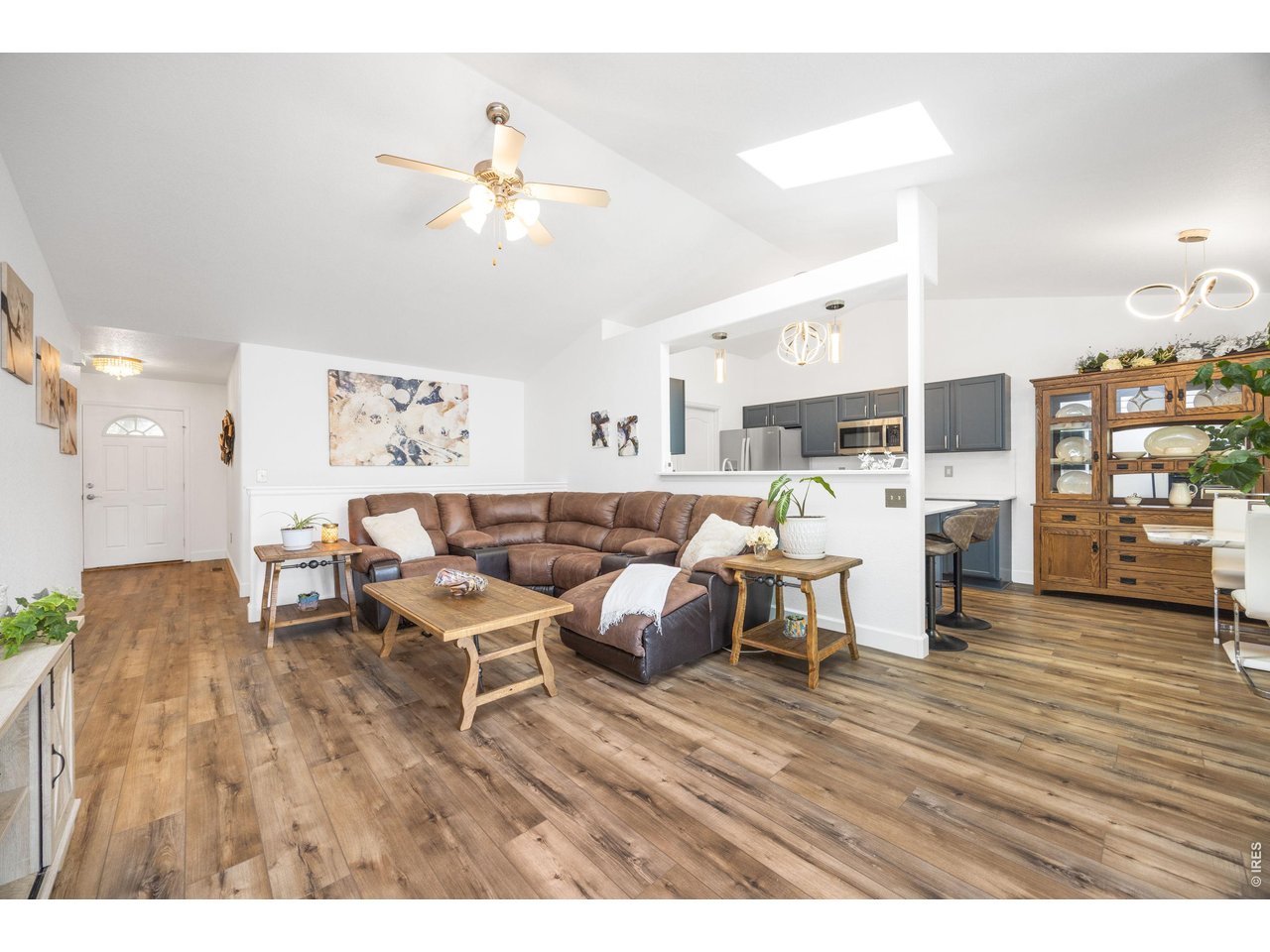 148 Beacon Way Windsor, CO 80550 - Photo 8 of 36 Expansive open concept living and dining area featuring vaulted ceilings, updated flooring, breakfast bar seating, skylight, and seamless flow into the kitchen and dining space.