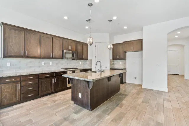 a large kitchen with stainless steel appliances granite countertop a stove and a sink