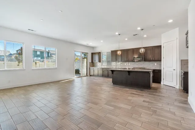 a large kitchen with stainless steel appliances granite countertop a stove a sink dishwasher and a refrigerator with wooden floor