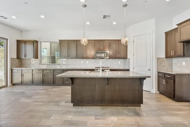 a large kitchen with stainless steel appliances kitchen island granite countertop a sink and cabinets