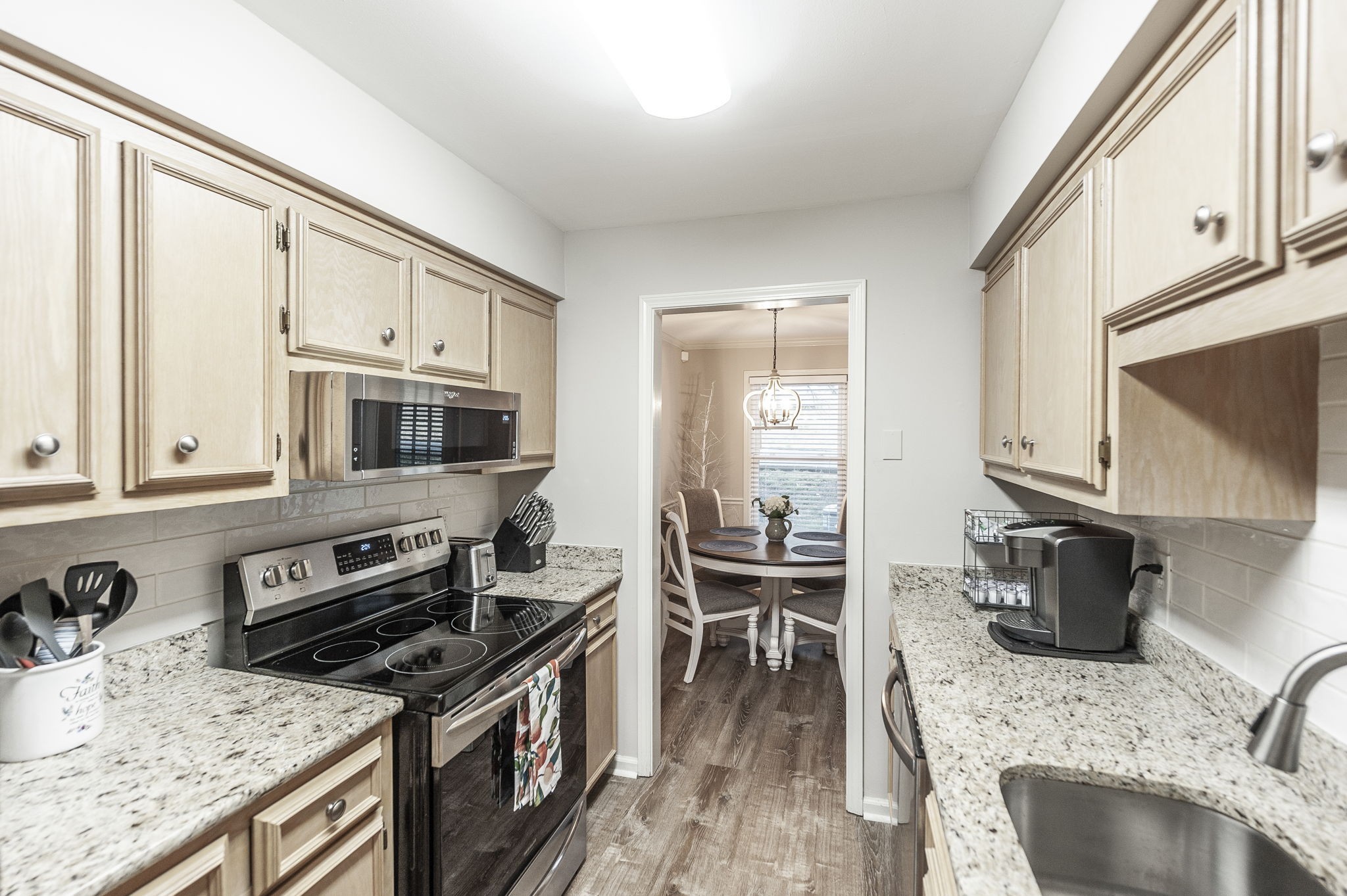 205 Churchill Crossing Madison, TN 37115 - Photo 9 of 17 a kitchen with stainless steel appliances granite countertop a stove top oven a sink a dining table and chairs with wooden floor