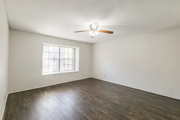 an empty room with wooden floor and chandelier fan