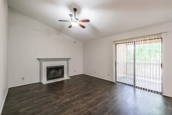 a view of an empty room with wooden floor fireplace and a window
