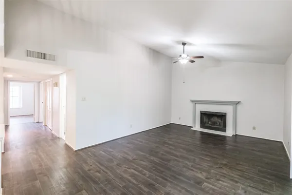 a view of an empty room with wooden floor fireplace and a window