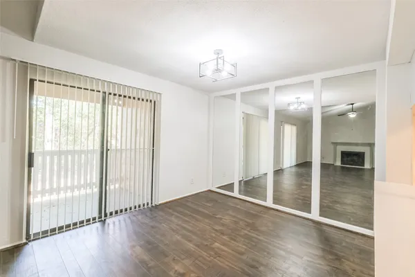 an empty room with wooden floor mirror and windows