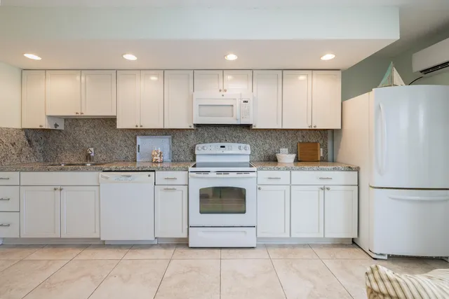 a kitchen with granite countertop white cabinets white stainless steel appliances and a sink