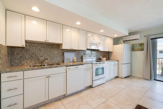 a kitchen with granite countertop white cabinets and white appliances