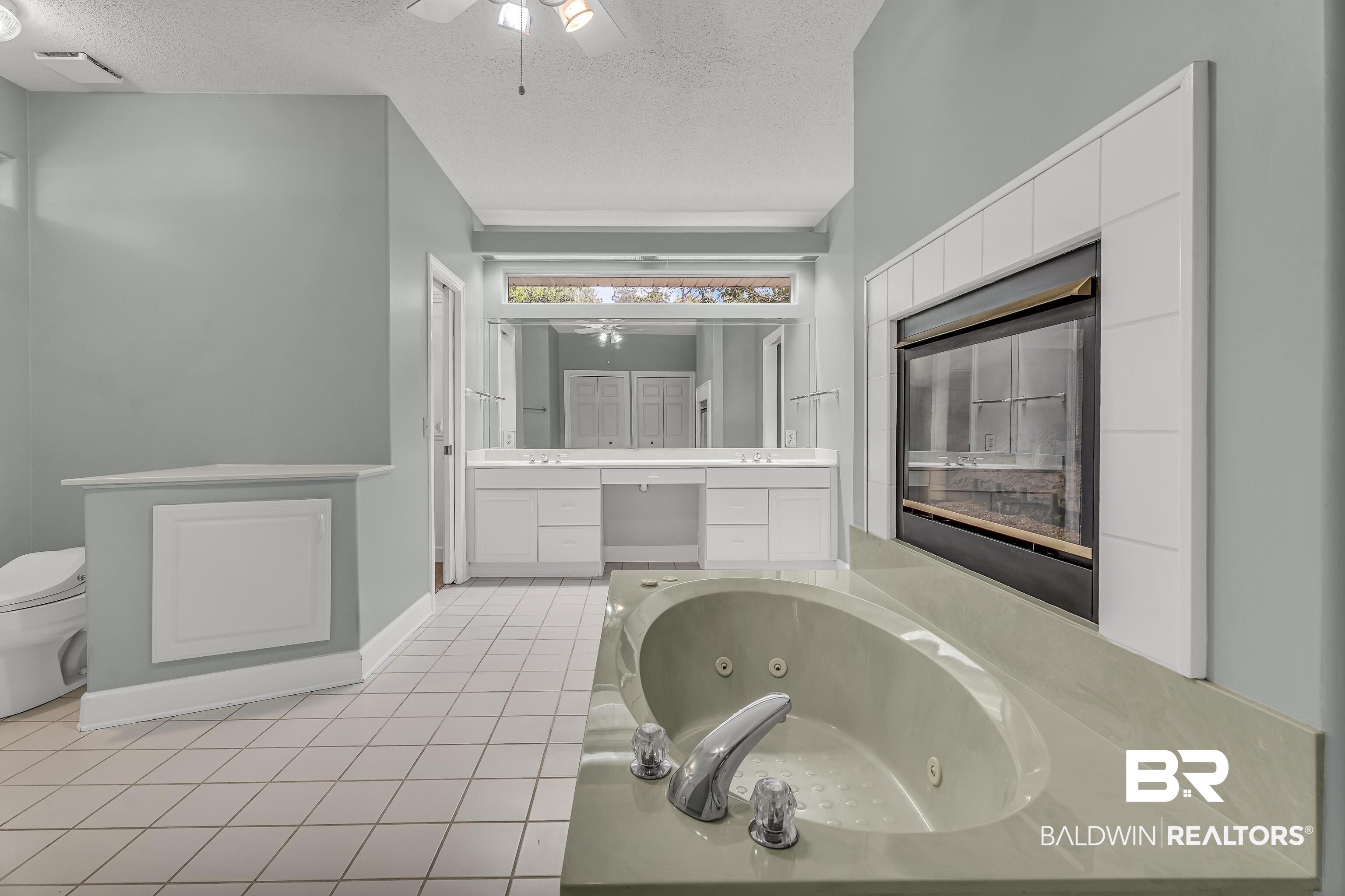 9530 Pilgrim Drive Elberta, AL 36530 - Photo 9 of 61 Bathroom featuring vanity, a whirlpool tub, a textured ceiling, tile patterned floors, and a ceiling fan