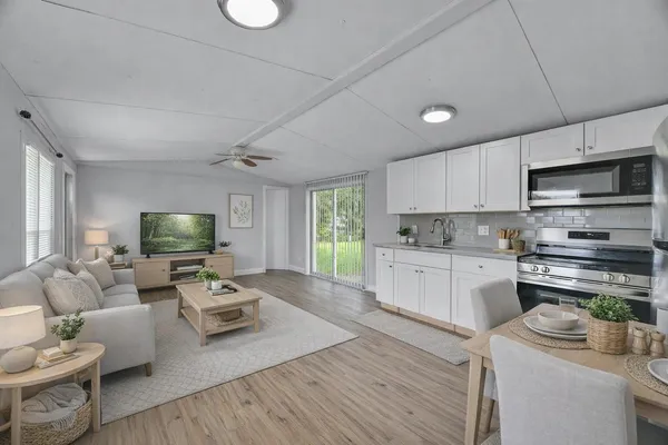 a living room with furniture a flat screen tv and kitchen view