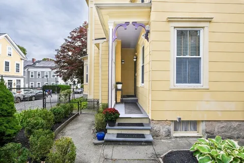 a view of a house with a small yard and large tree