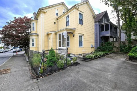 a view of a white house with large windows and a large tree