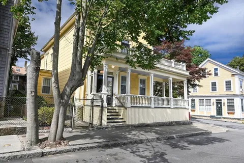 a view of a white house with large windows and a small yard