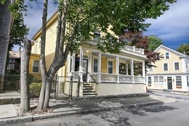 a view of a white house with large windows and a small yard
