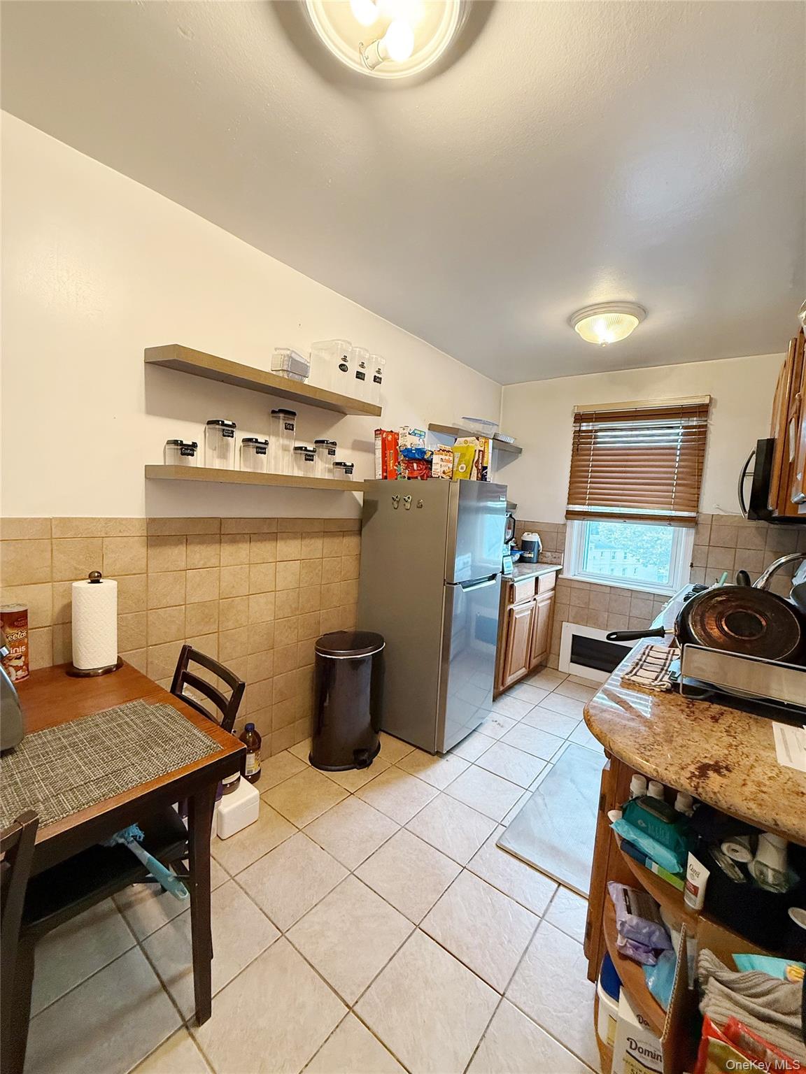 7103 252nd Street, Unit 199B Queens, NY 11426 - Photo 11 of 11 Kitchen with tile walls, freestanding refrigerator, light tile patterned flooring, a wainscoted wall, and light countertops