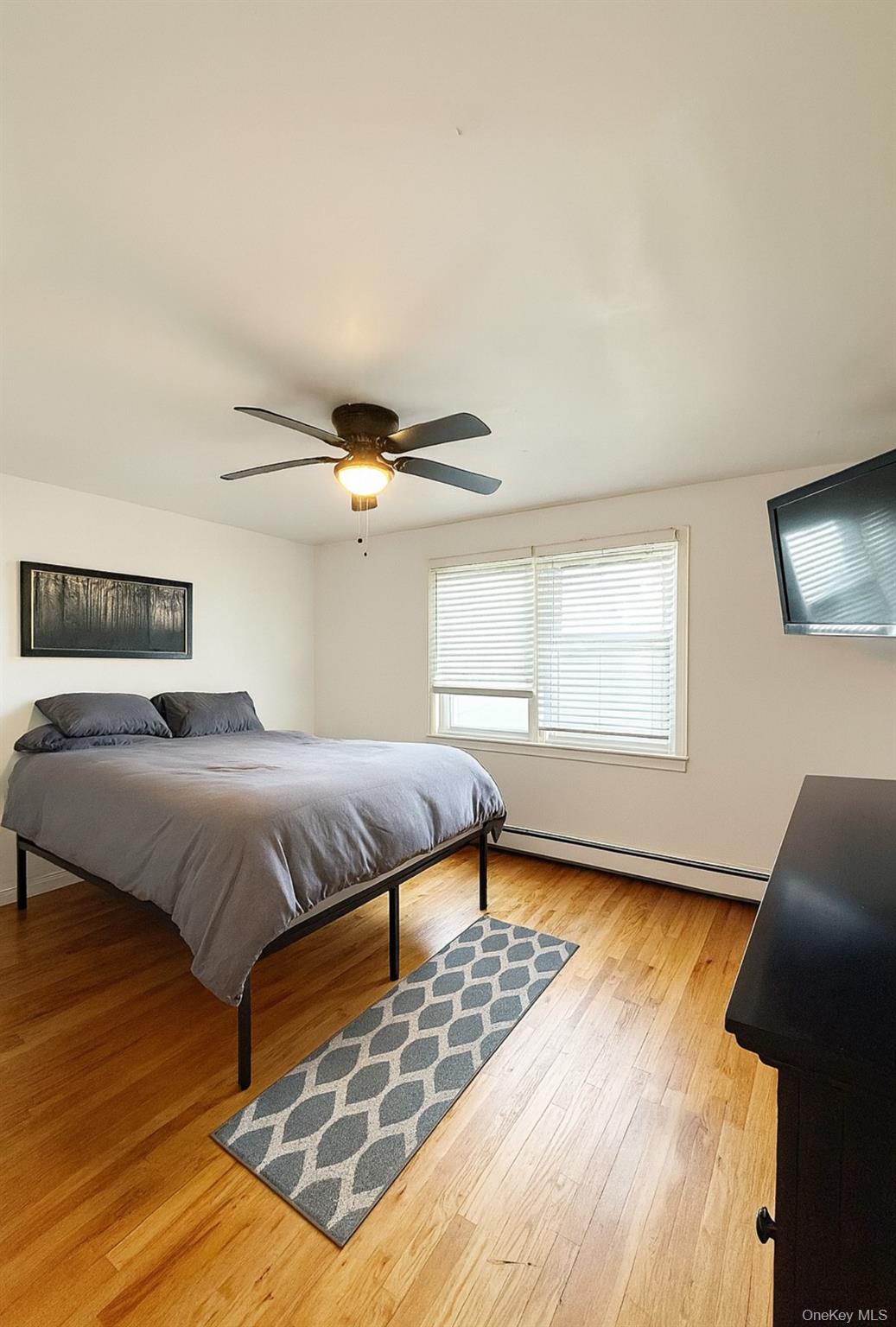 7103 252nd Street, Unit 199B Queens, NY 11426 - Photo 4 of 11 Bedroom with baseboard heating, ceiling fan, and light wood finished floors